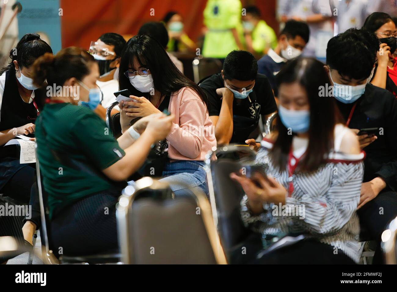 Bangkok, Thaïlande. 12 mai 2021. Les gens utilisent leur téléphone mobile après avoir été vaccinés avec la dose du vaccin CoronaVac à Bangkok. Selon un haut fonctionnaire du ministère de la Santé publique, les autorités sanitaires ont maintenant pour objectif de faire vacciner environ 70 % des habitants de la capitale, soit environ 5 millions de personnes contre Covid-19 en deux mois. La décision a été suivie par le Premier ministre Prayut Chan-o-cha mardi, qui a exprimé des inquiétudes au cours de la réunion du cabinet, à savoir que le nombre de personnes qui se sont inscrites à la vaccination auprès du gouvernement était inférieur à la cible. Crédit : SOPA Images Limited/Alamy Live News Banque D'Images