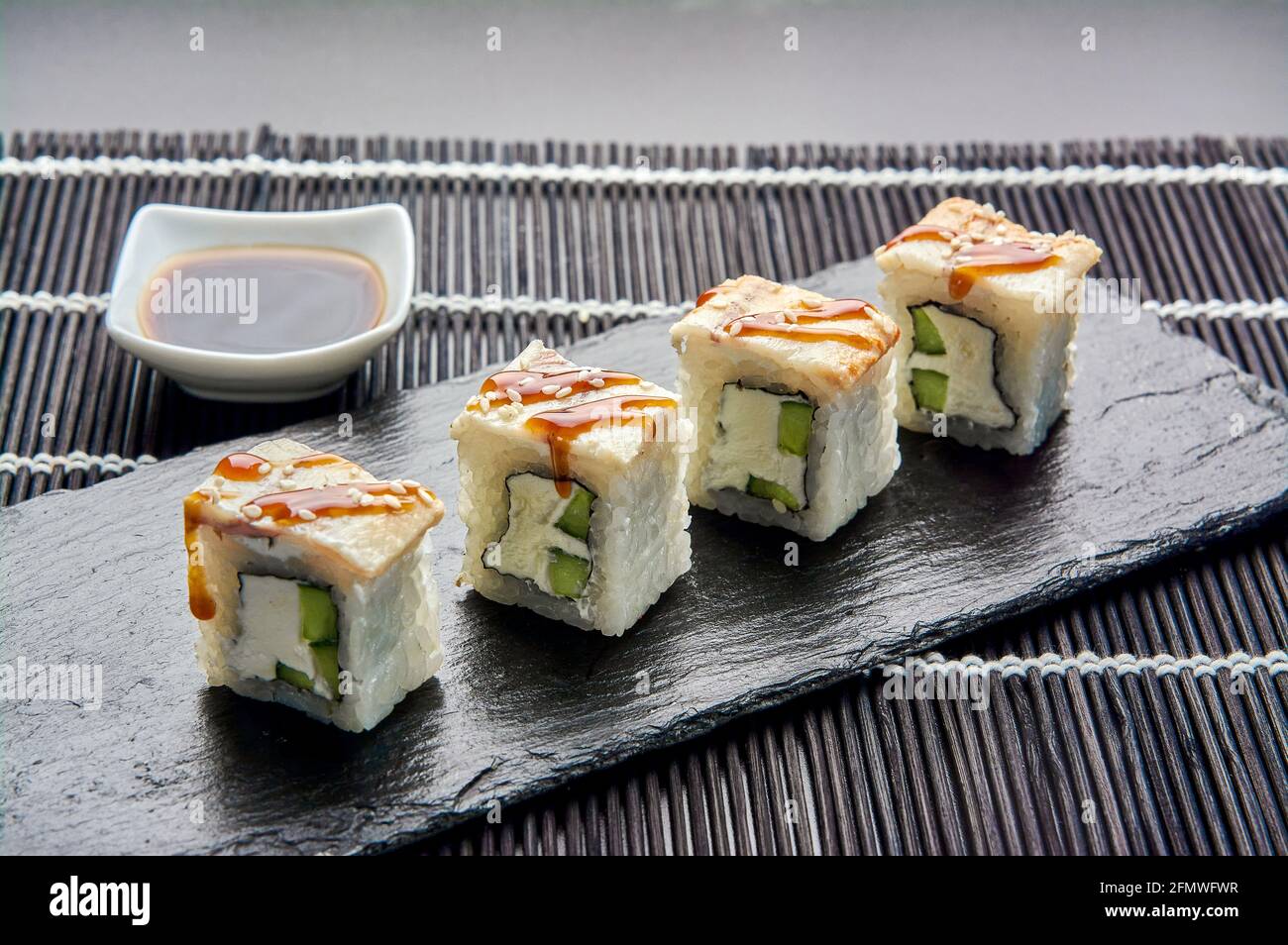 Philadelphie avec un concombre sur une pierre sombre. Sushi japonais. Banque D'Images