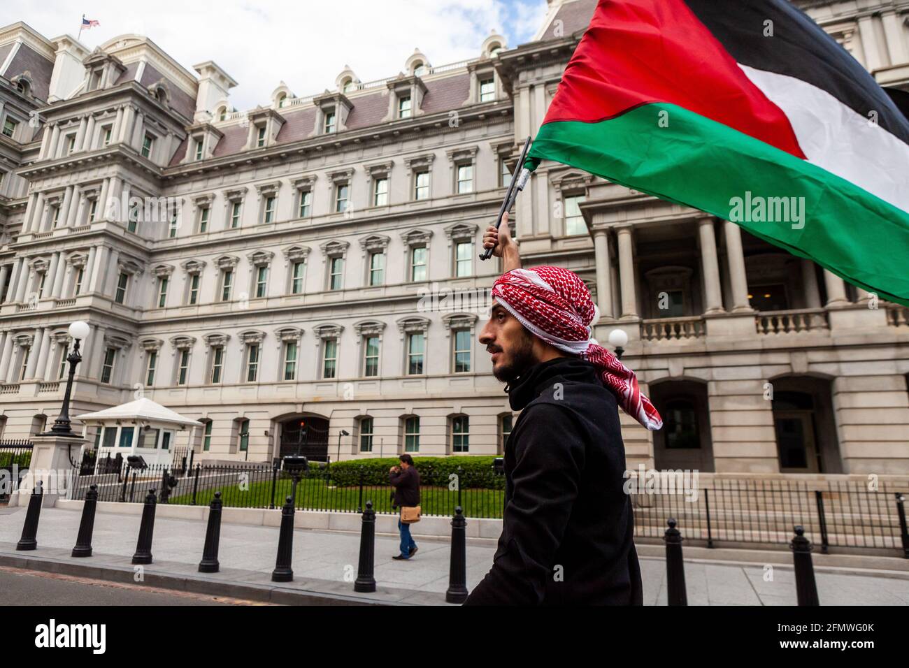 Washington, DC, Etats-Unis, 11 mai 2021. Photo : un manifestant porte un drapeau palestinien alors qu'il passe devant le bâtiment du bureau exécutif et le bureau du vice-président pendant une marche appelant les États-Unis à cesser de financer l'apartheid, l'occupation et la violence en Palestine. Crédit : Allison C Bailey / Alamy Live News Banque D'Images