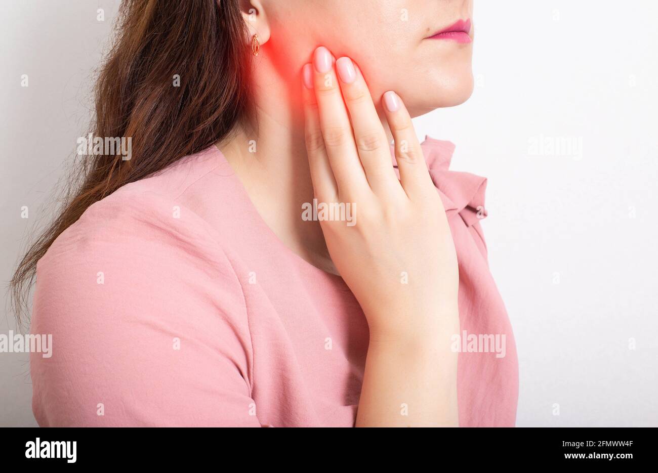 Belle fille tenant sa main sur la mâchoire inférieure de la dent, qui a un nerf de dent enflammé, abcès dentaire Banque D'Images