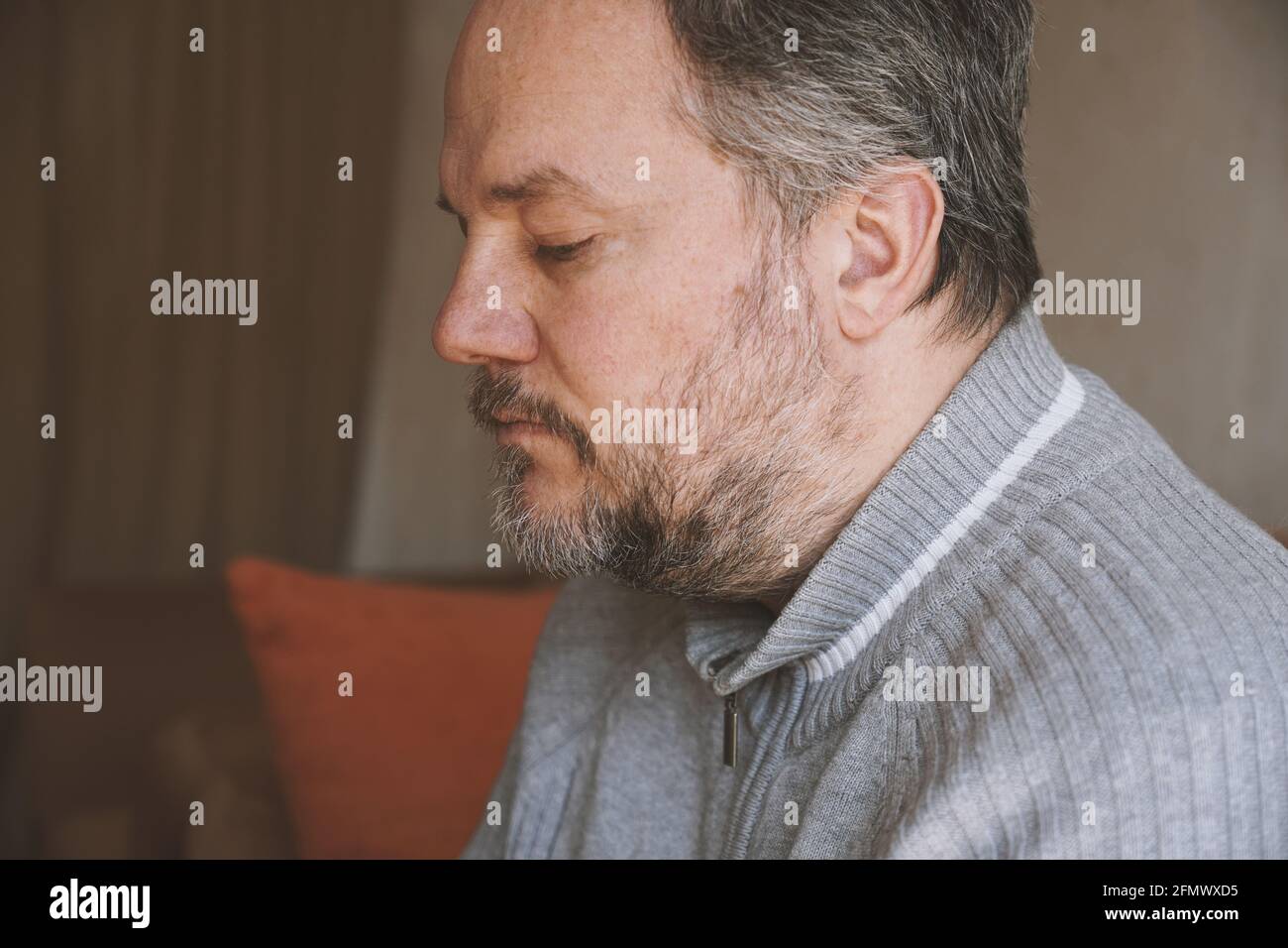 homme d'âge moyen seul à la maison et regardant vers le bas et déprimé Banque D'Images