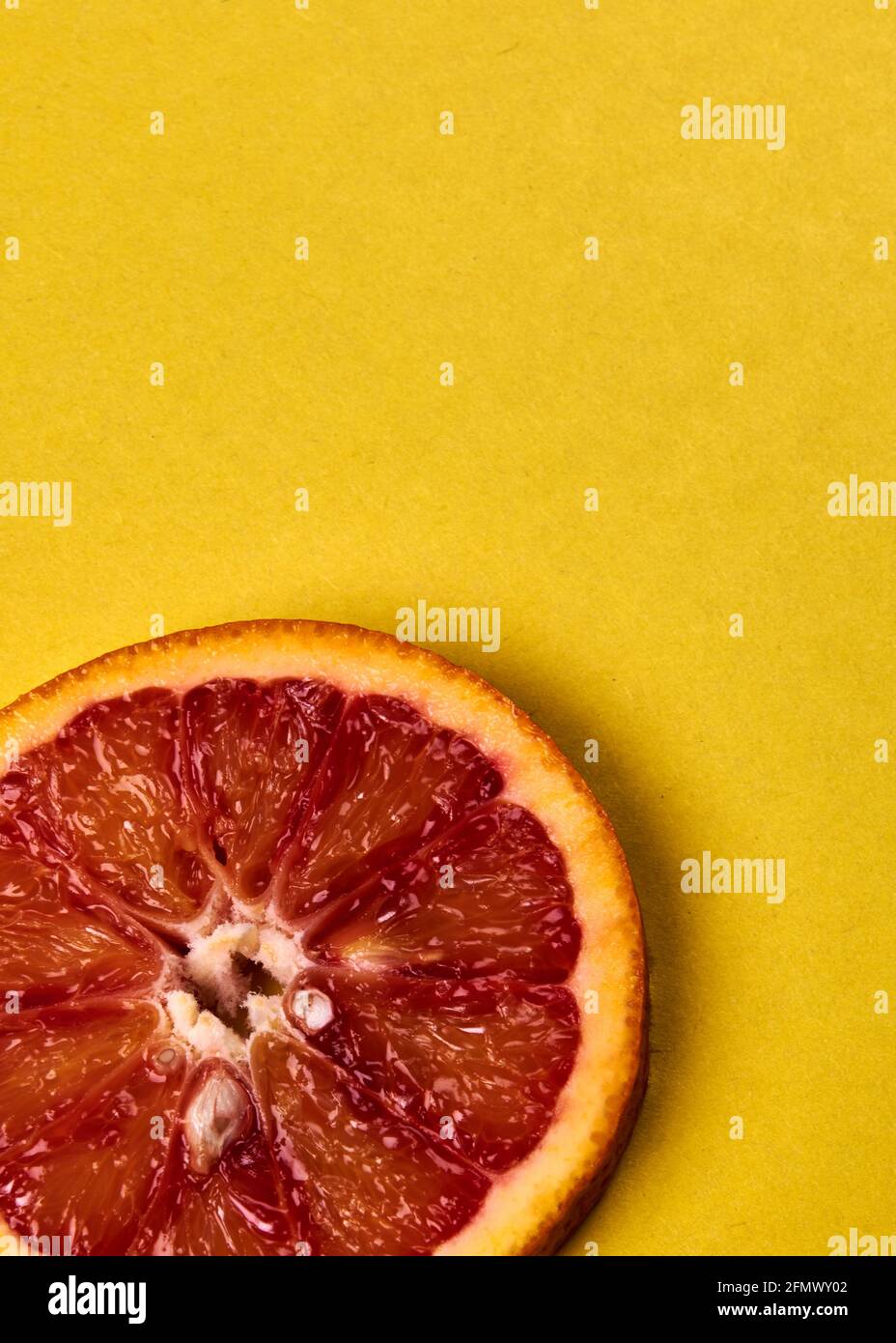 une tranche de mandarine rouge sur fond jaune Banque D'Images