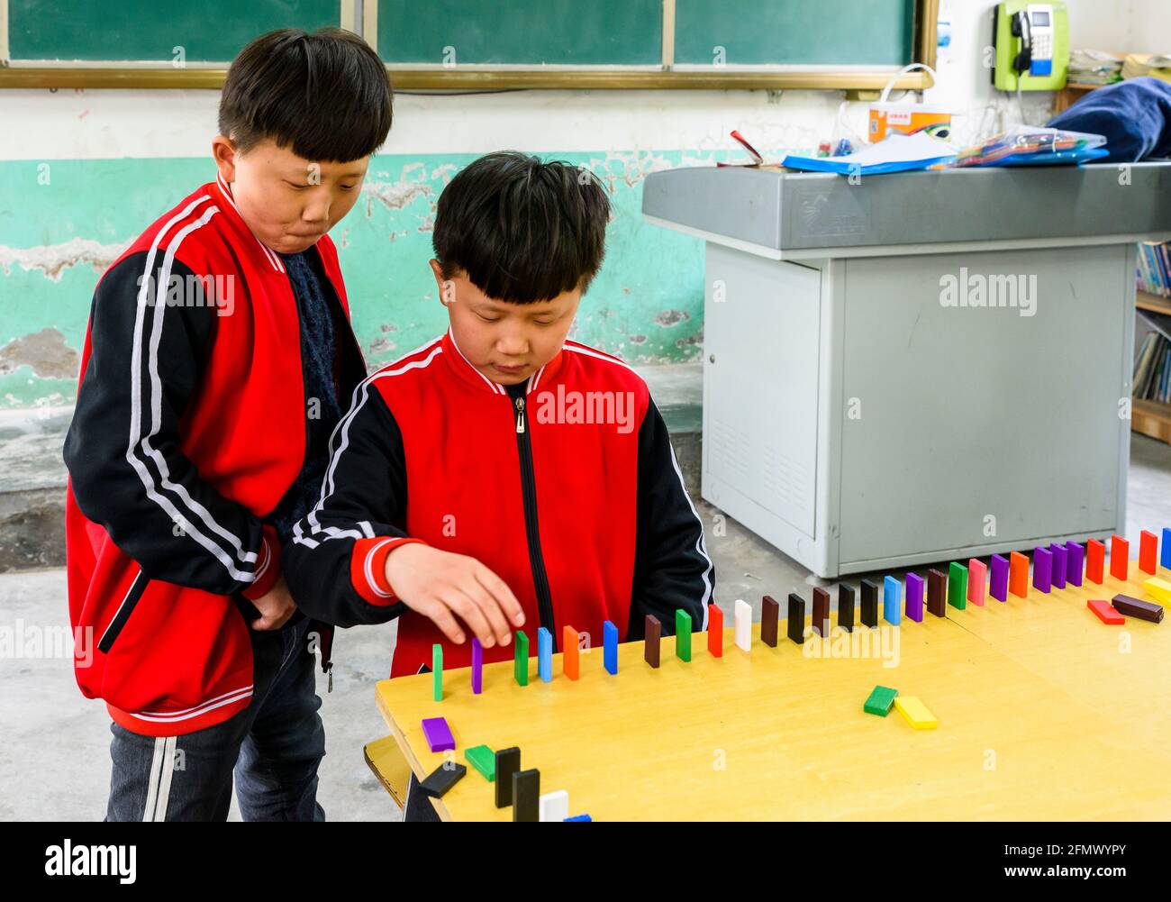 Élèves du primaire qui sont jumeaux jouant des dominos dans une école rurale de Qufu, Shandong, Chine. Banque D'Images