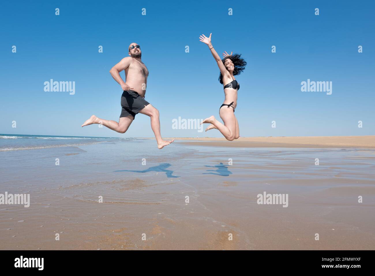 jeune couple en vacances riant et appréciant tout en sautant et en courant sur une plage solitaire. concept de loisirs et de vacances Banque D'Images