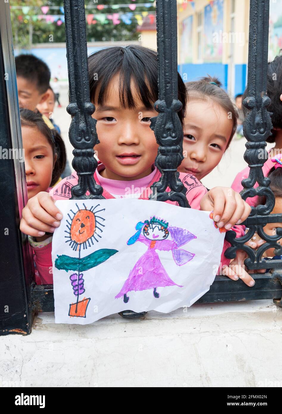 Une étudiante de maternelle dans une école rurale en Chine donne son dessin à l'enseignant. Banque D'Images