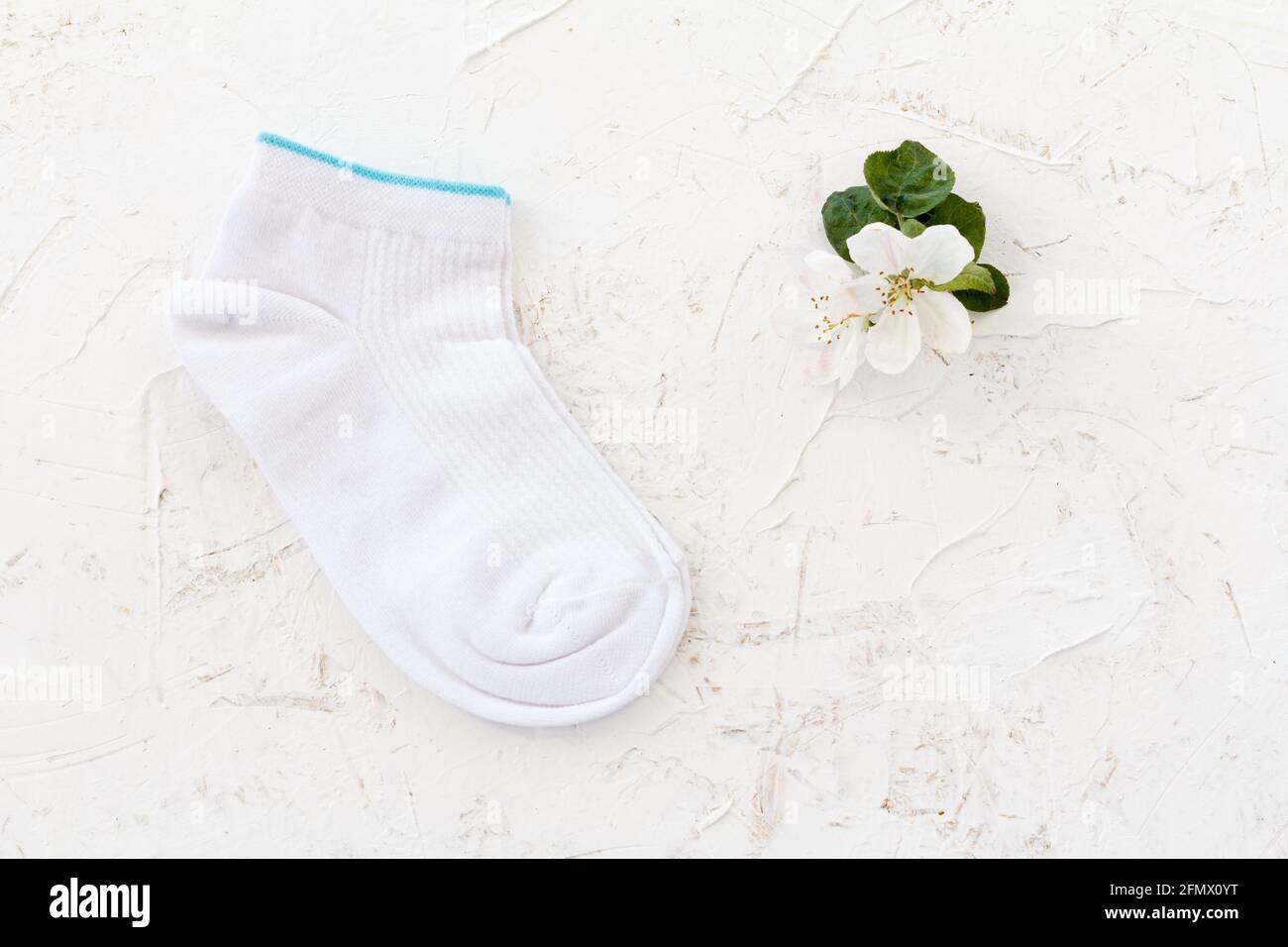 Paire de femmes chaussettes et fleurs d'un pommier sur le fond blanc structuré, vue du dessus. Banque D'Images