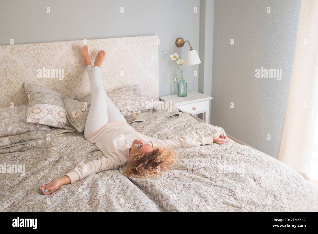 Maison style de vie femme se relaxant le matin sur le lit dans la chambre à coucher  de la maison. Bonne dame couchée sur un matelas confortable prenant une  sieste pour le