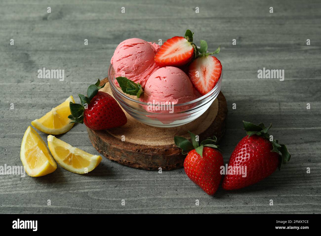 Bol avec boules de crème glacée et ingrédients sur texture grise arrière-plan Banque D'Images