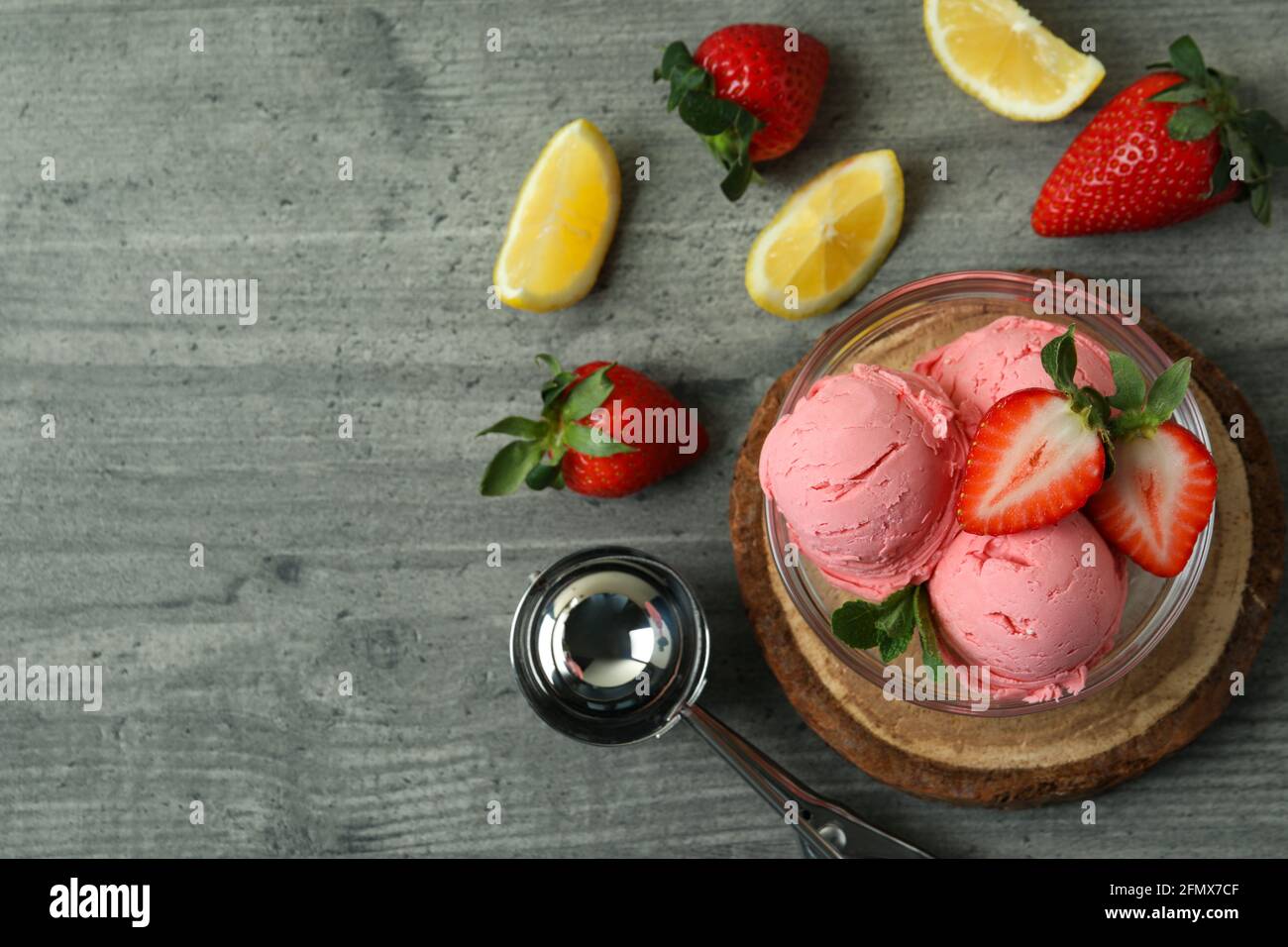 Bol avec boules de crème glacée et ingrédients sur texture grise arrière-plan Banque D'Images