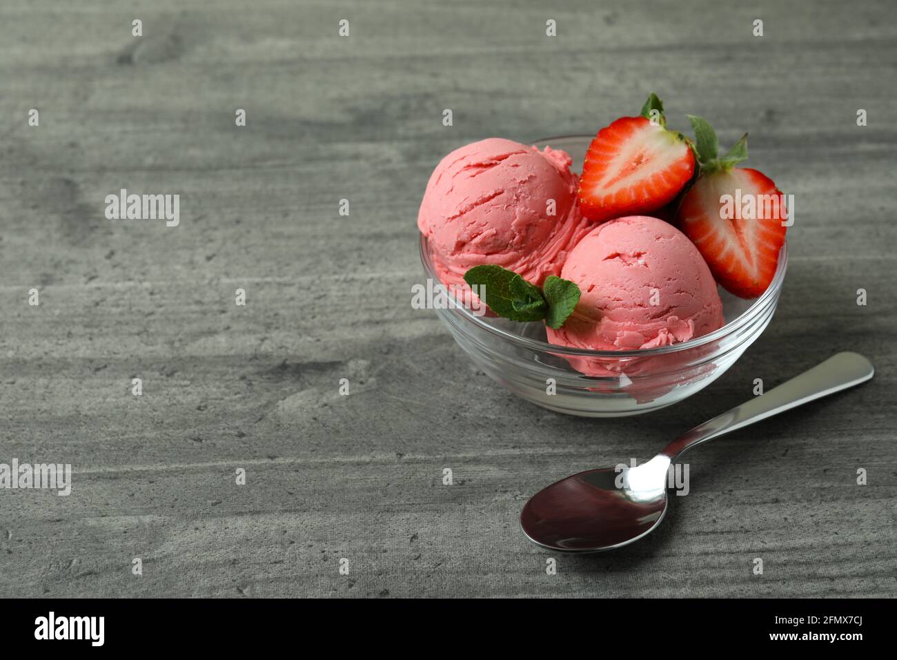 Bol avec boules de glace à la fraise sur table texturée grise Banque D'Images