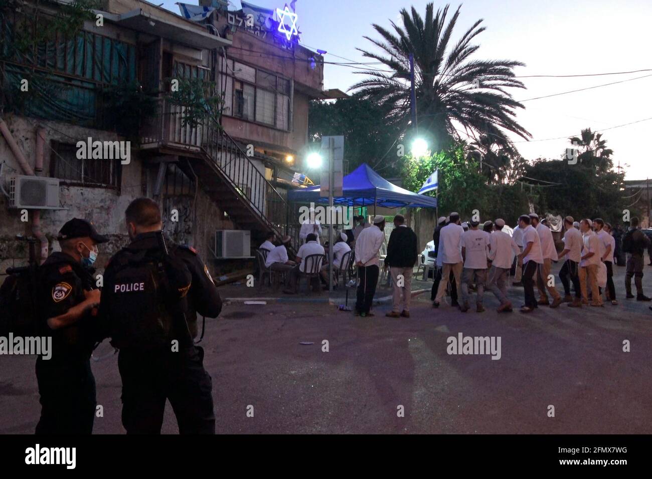 La police garde les colons juifs chantant et dansant devant une maison occupée par des colons juifs dans le quartier de Sheikh Jarrah, un quartier majoritairement palestinien, le 07 mai 2021, à Jérusalem-est, en Israël. Des dizaines de résidents palestiniens de Sheikh Jarrah ont été victimes d’évictions potentielles pendant des années, dans le cadre d’efforts intensifiés de la part de groupes de colons de droite qui affirment que la terre appartenait aux juifs avant 1948, date de la fondation d’Israël. La menace d'expulsion a conduit à de fréquentes manifestations. Banque D'Images