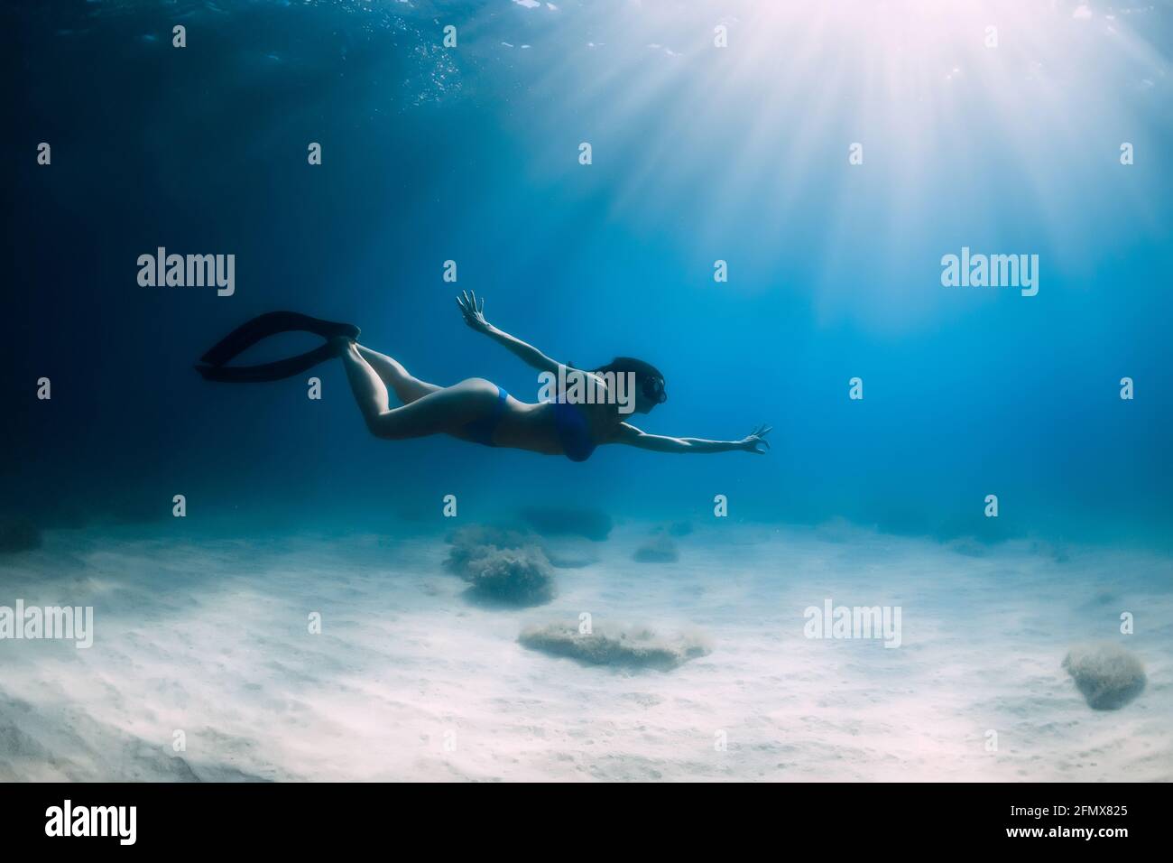 Belle femme de frediver avec nageoires plongée sous l'eau profonde dans la mer. Banque D'Images