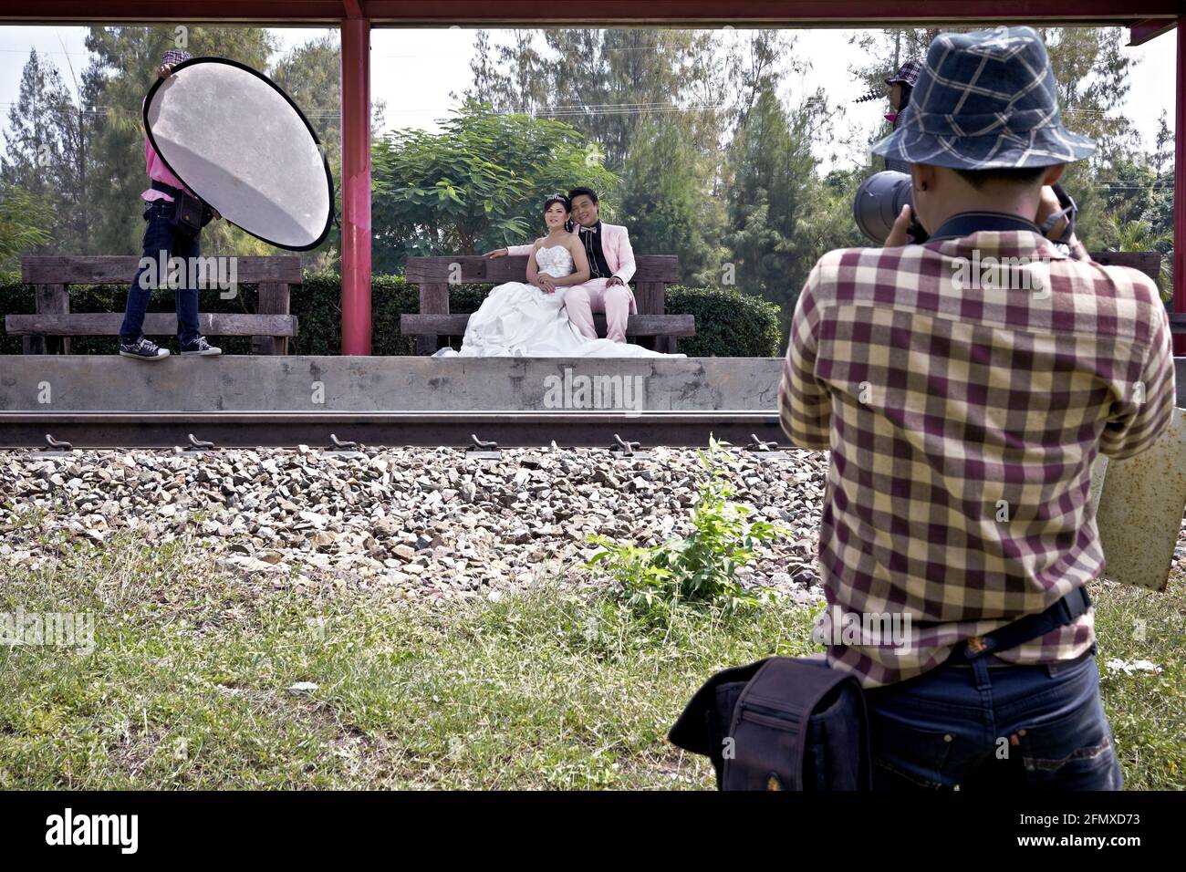 Photographe de mariage prenant des photos avec mariée et marié sur une voie ferrée. Emplacement inhabituel. Banque D'Images