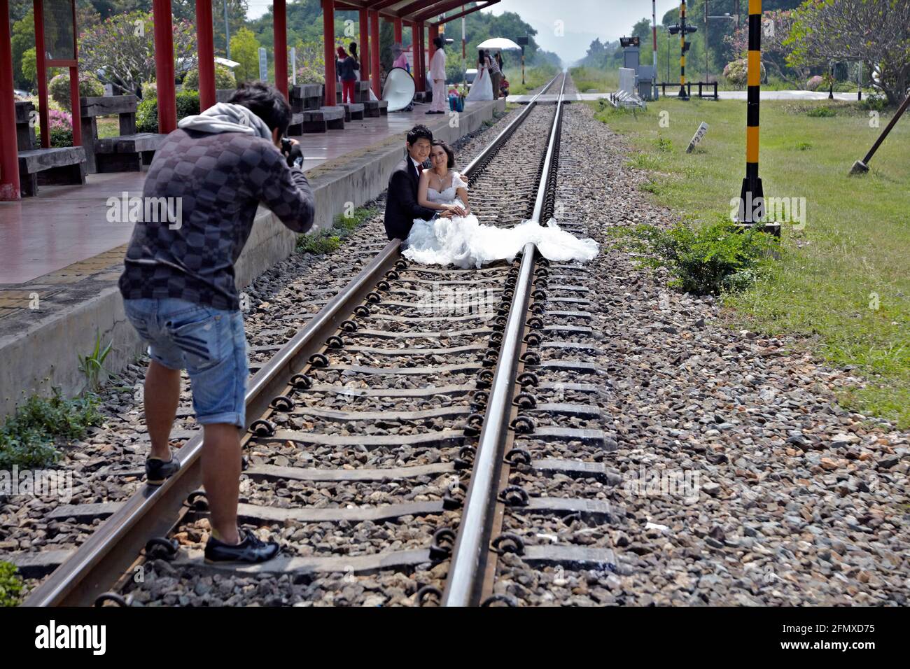 Photographe de mariage prenant des photos avec mariée et marié sur une voie ferrée. Emplacement inhabituel. Banque D'Images
