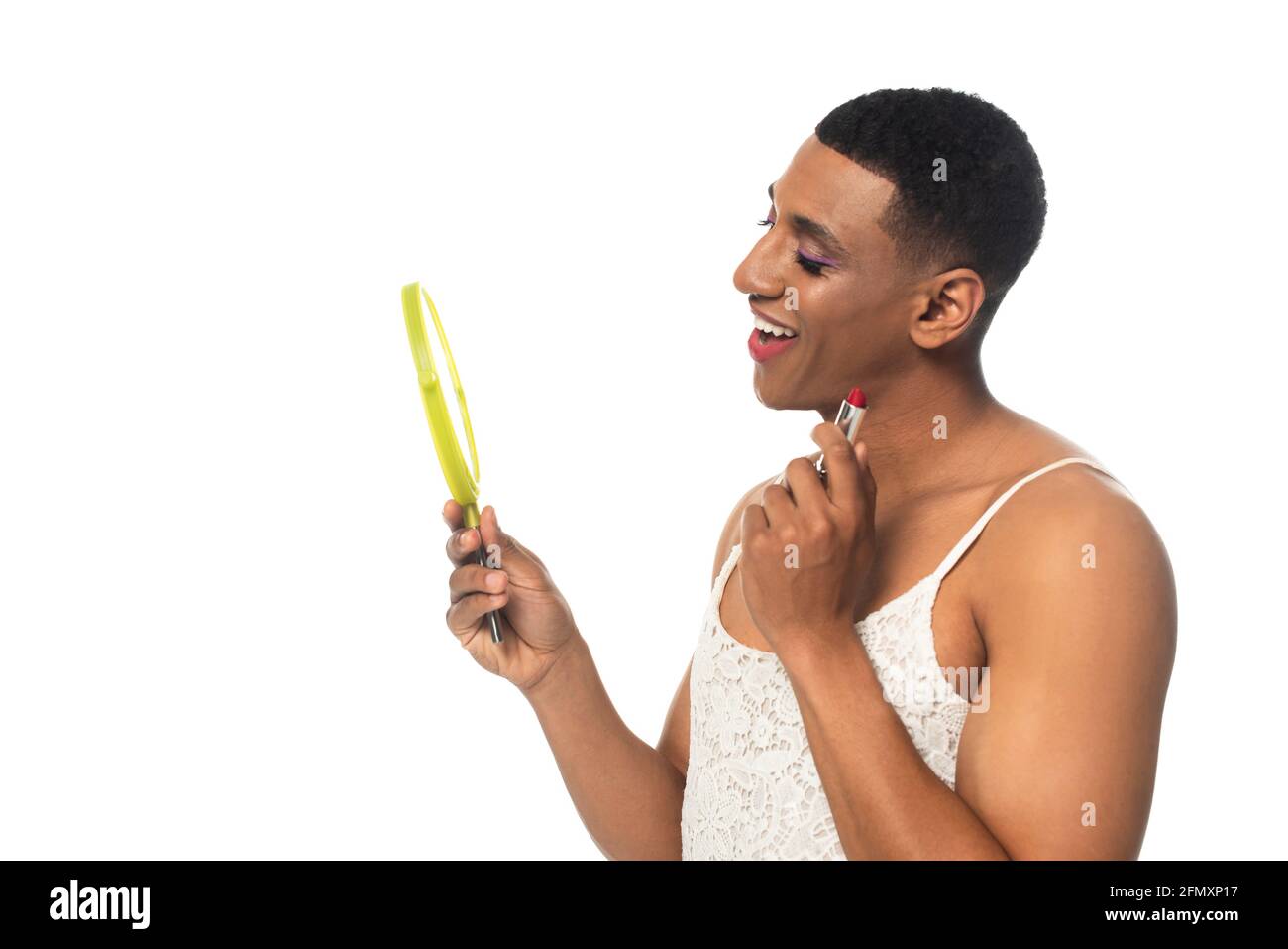 homme transsexuel afro-américain souriant tout en tenant le rouge à lèvres et le miroir isolé sur blanc Banque D'Images