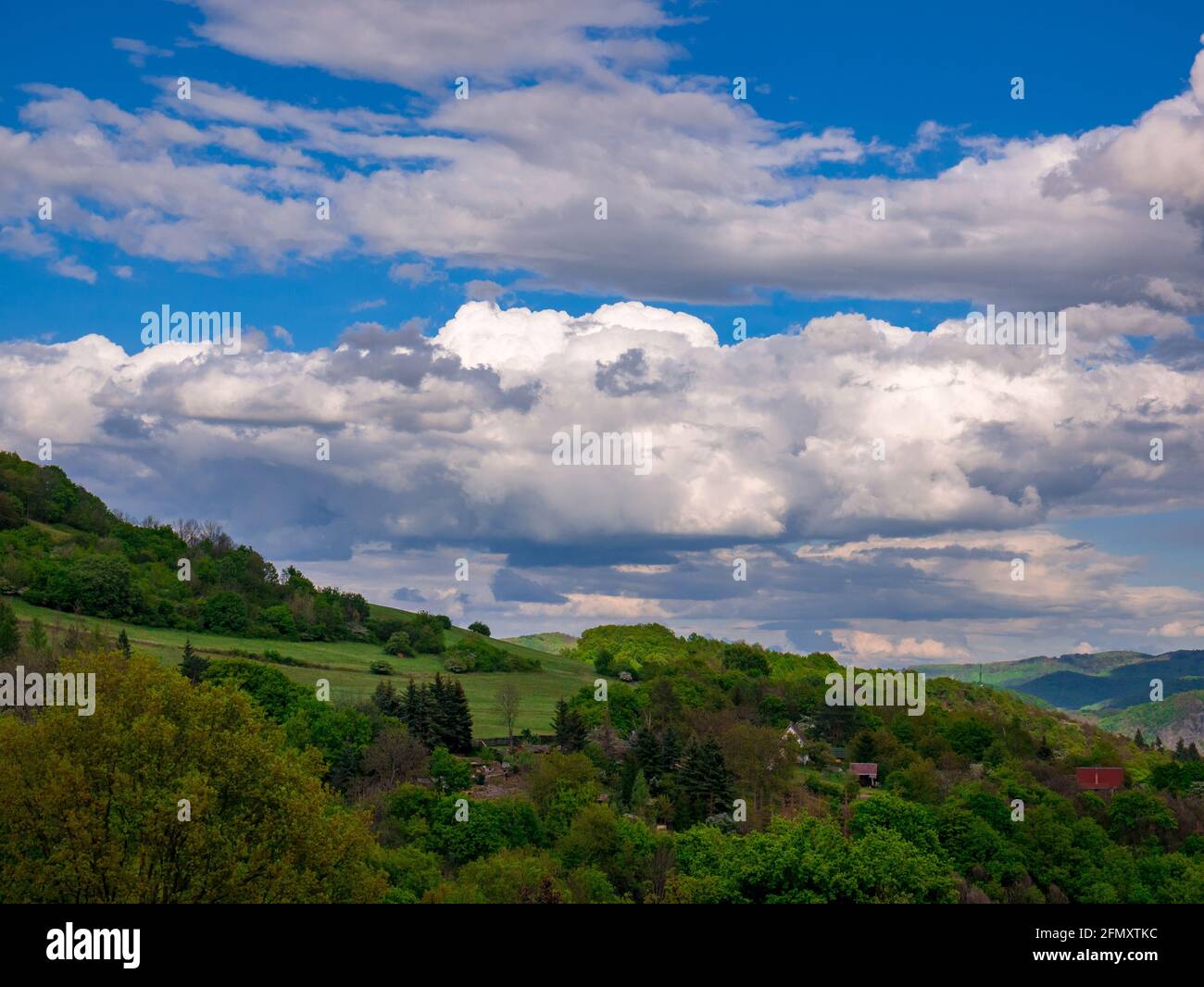 Nuages massifs - Cumulonimbus - se formant dans le ciel bleu paysage vallonné Banque D'Images