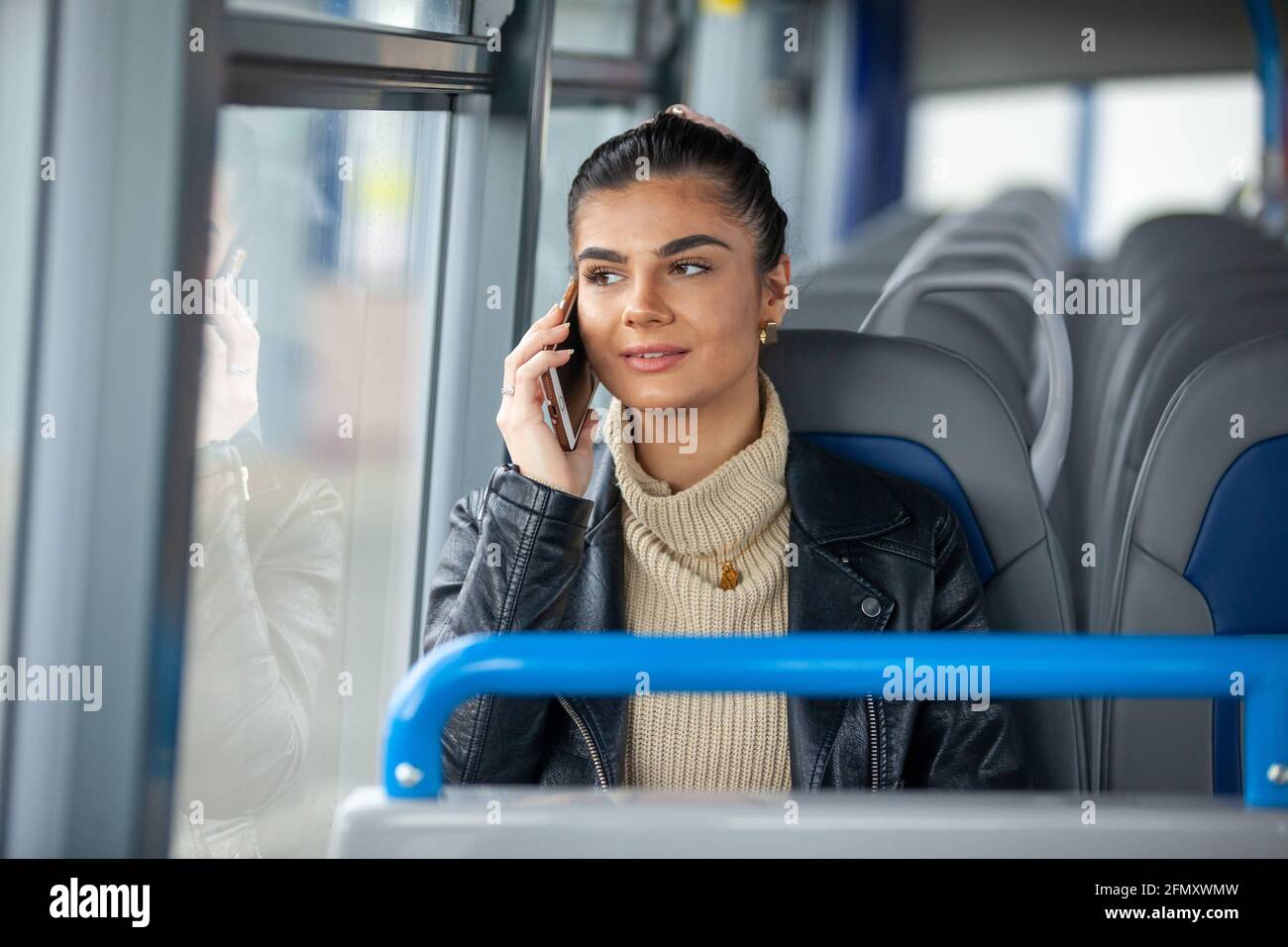 Une femme tenant son téléphone portable à l'oreille un bus Banque D'Images