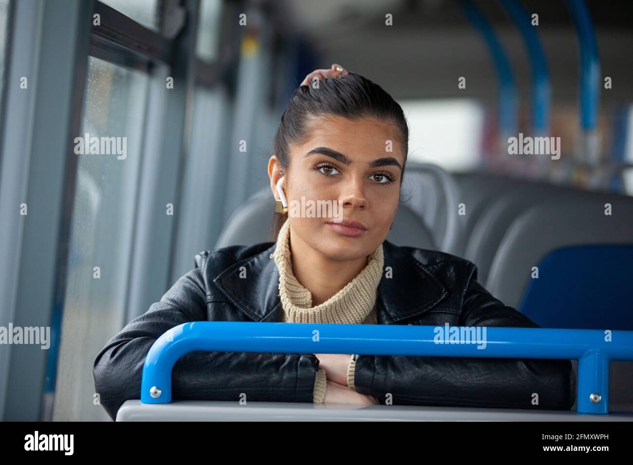 Une femme assise dans un bus à l'écoute de musique et regarder l'appareil photo Banque D'Images