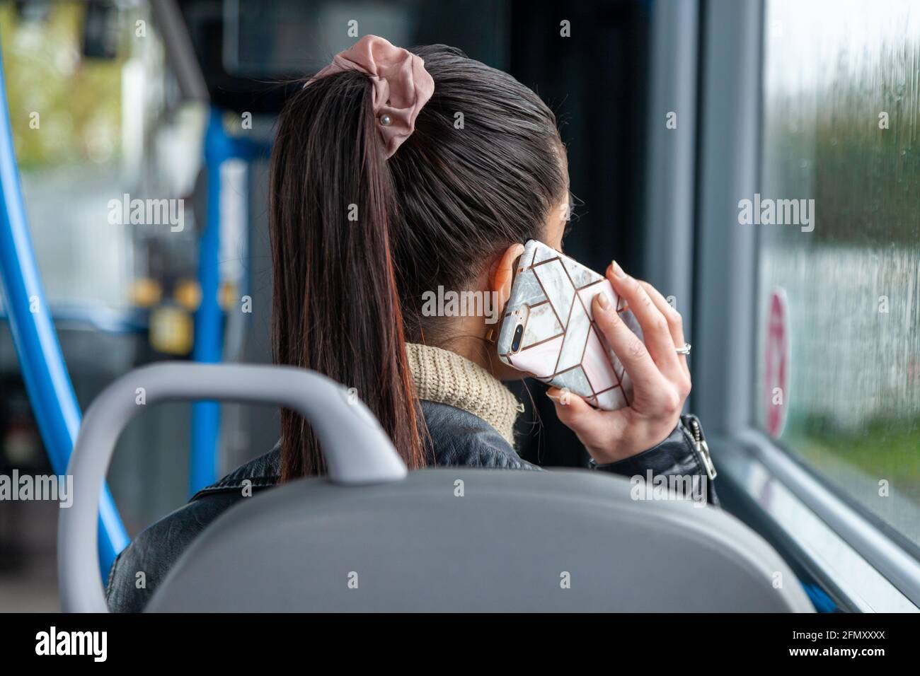 une femme assise dans un bus avec un téléphone portable à son oreille Banque D'Images
