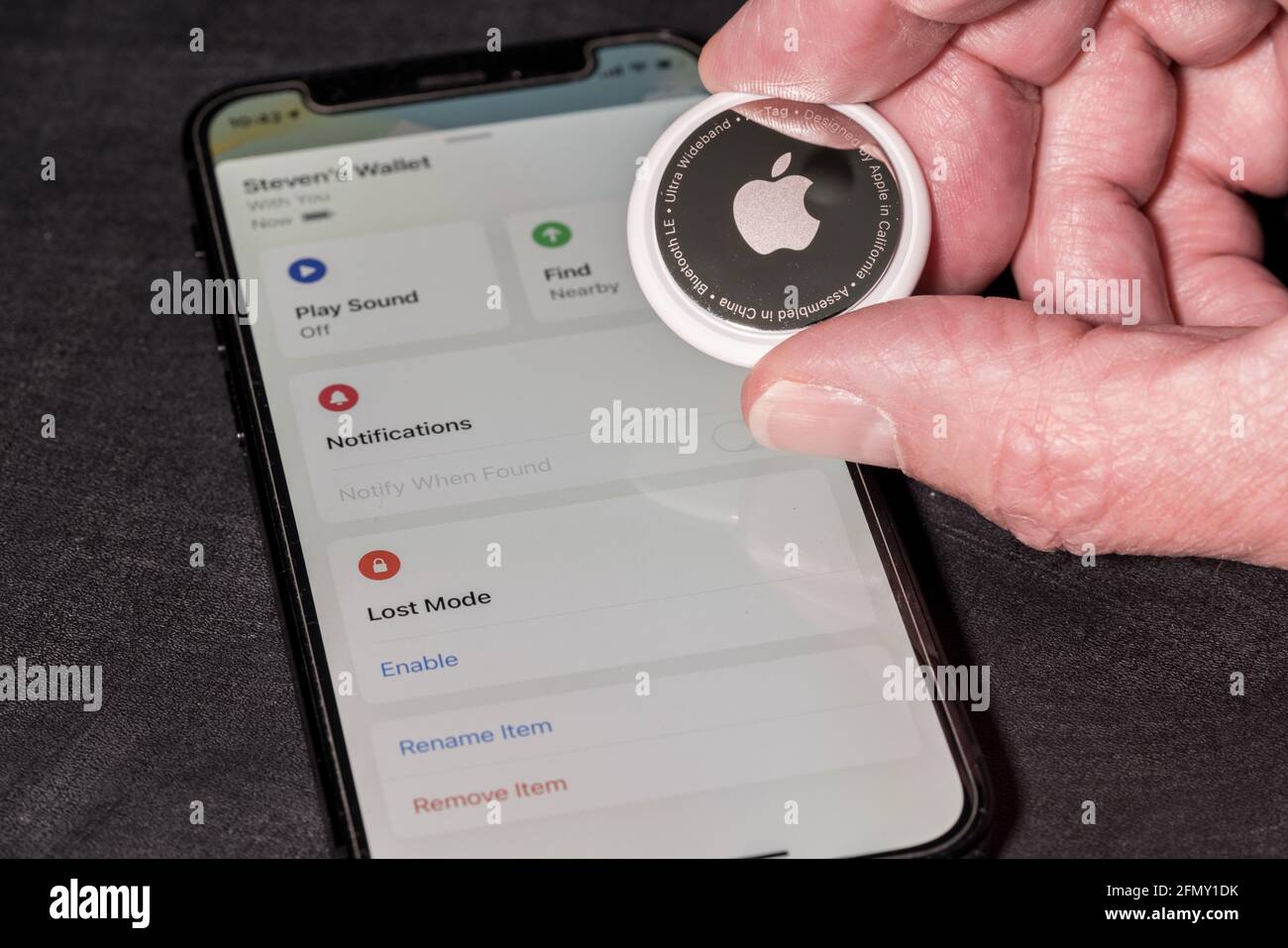 Morgantown, WV - 12 Mai 2021: Appareil AIRTAG Apple tenu dans la main causasienne senior au-dessus du mini smartphone iPhone Banque D'Images