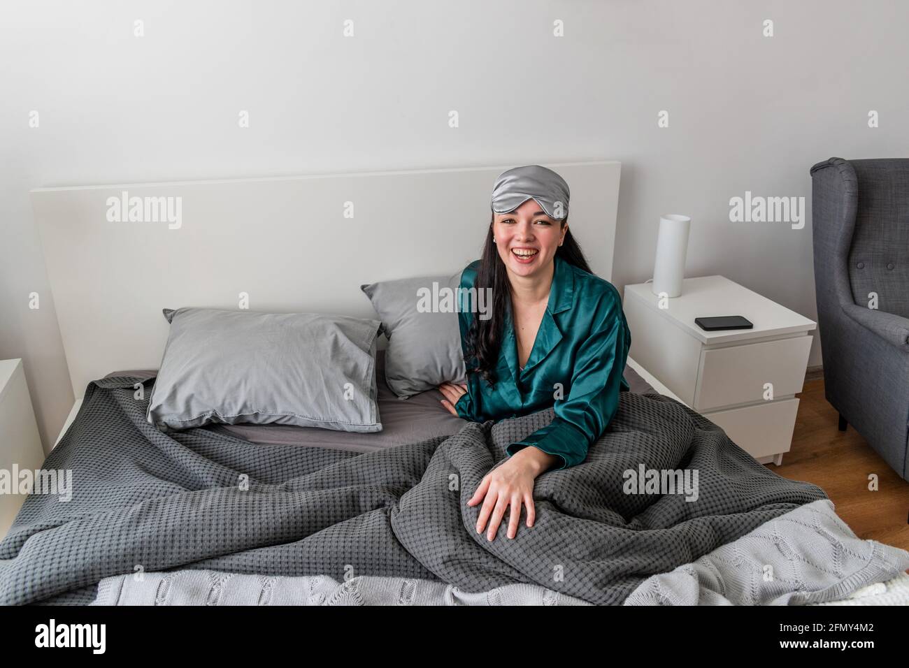 Une jeune femme en pyjama de soie repose dans un lit confortable et doux. Bien-être à la maison. Concept bien-être. Banque D'Images