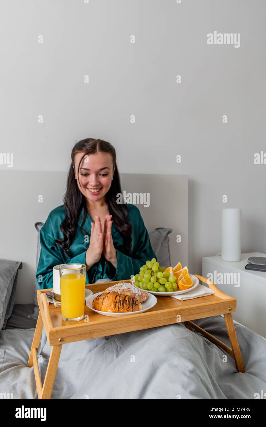 La jeune femme se réjouit de la surprise d'avoir le petit déjeuner au lit. Concept bien-être. Banque D'Images