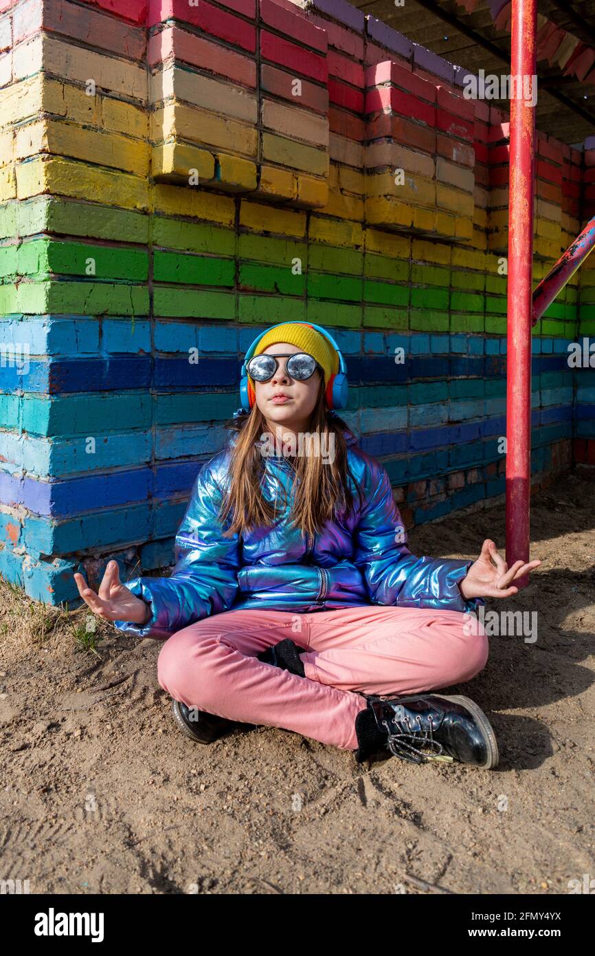 Une adolescente est assise dans la rue dans une position de lotus et médite. Concept bien-être. Banque D'Images