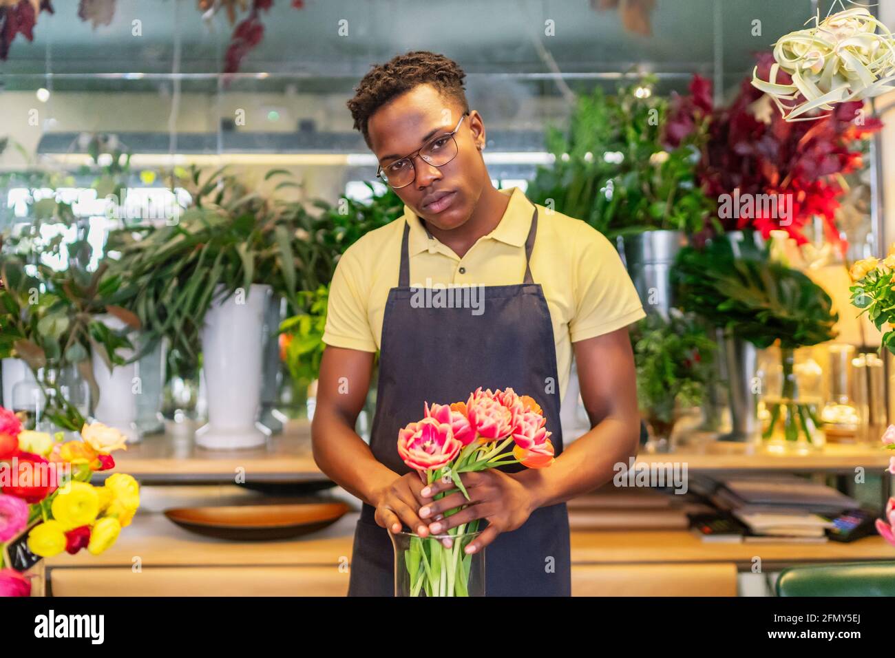 jeune entrepreneur africain regardant les fleurs de son entreprise Banque D'Images