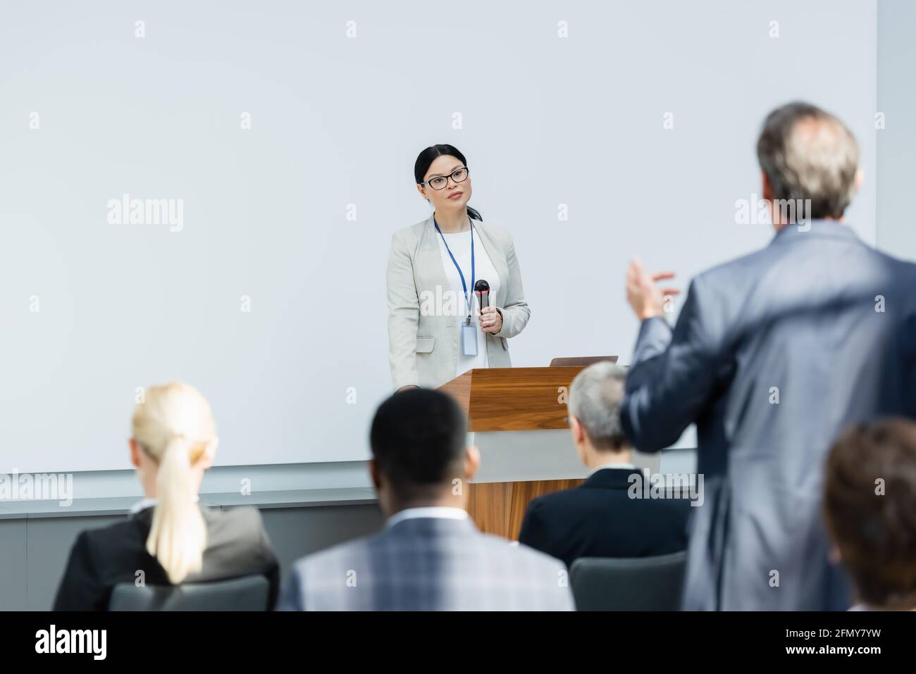 vue arrière d'un homme d'affaires parlant avec un orateur asiatique pendant la conférence Banque D'Images