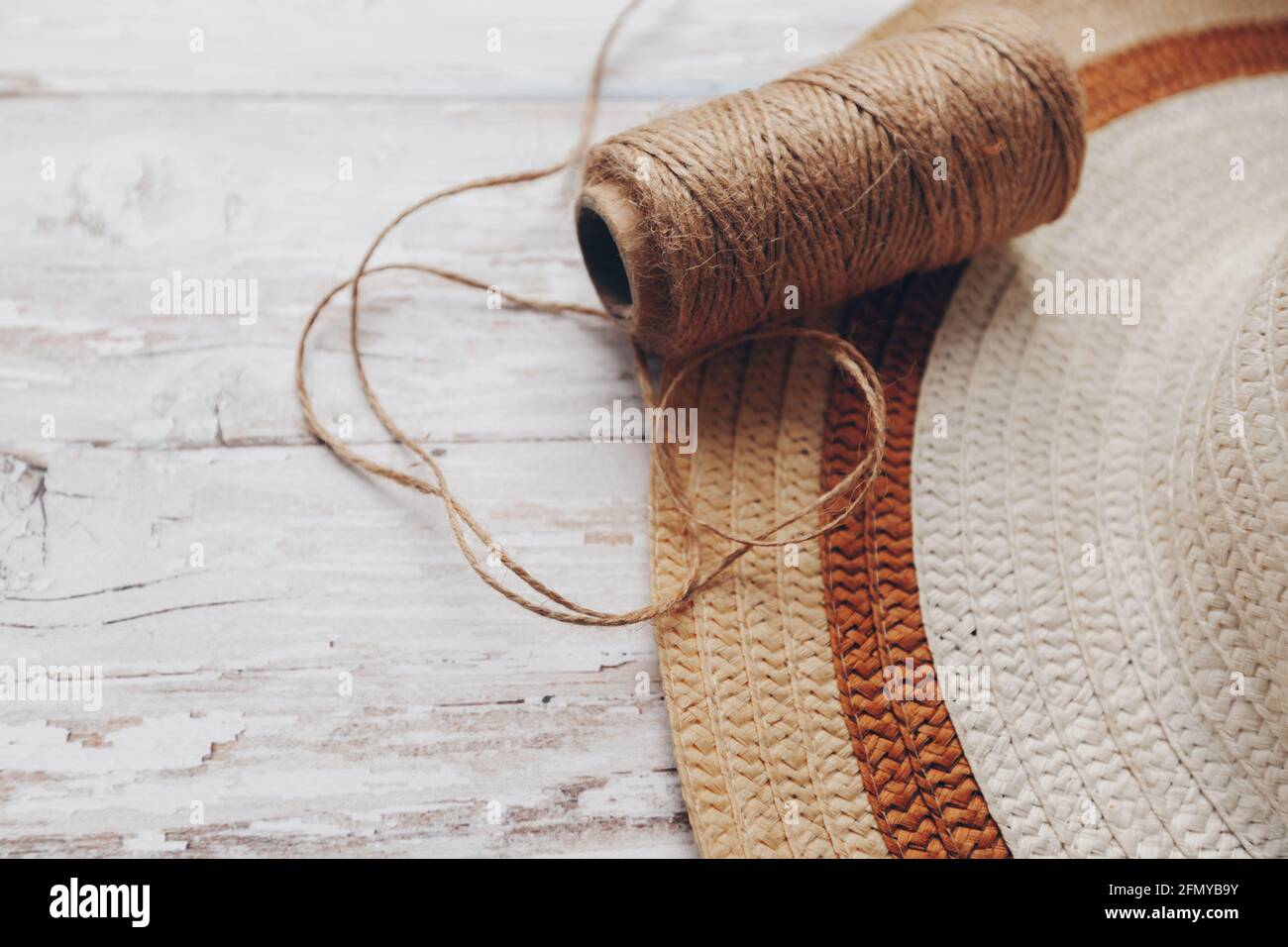 une pelote de ficelle beige et un chapeau de paille sur un fond en bois. ficelle pour le travail des aiguilles Banque D'Images