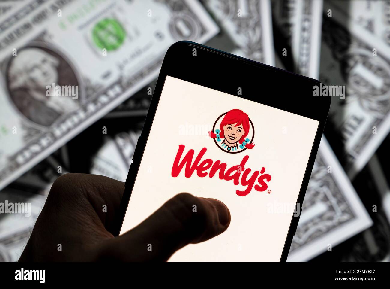 Chine. 21 avril 2021. Sur cette photo, le logo de la chaîne de restauration rapide américaine Wendy s'affiche sur un smartphone avec une devise en dollars américains (USD) en arrière-plan. Crédit: Budrul Chukrut/SOPA Images/ZUMA Wire/Alay Live News Banque D'Images