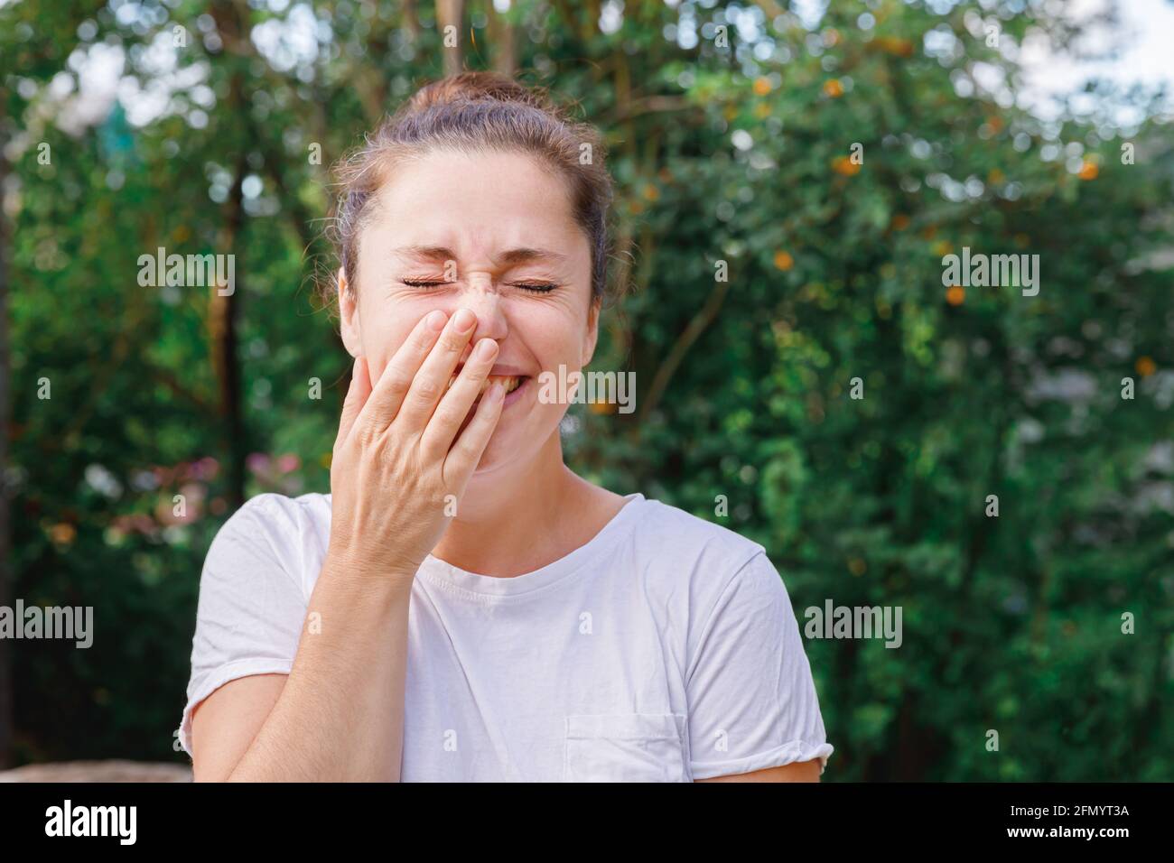 Jeune femme souriante à l'extérieur. Belle petite fille brunete reposant sur un parc ou un jardin vert. Femme heureuse gratuite en été. Liberté bonheur soins Banque D'Images