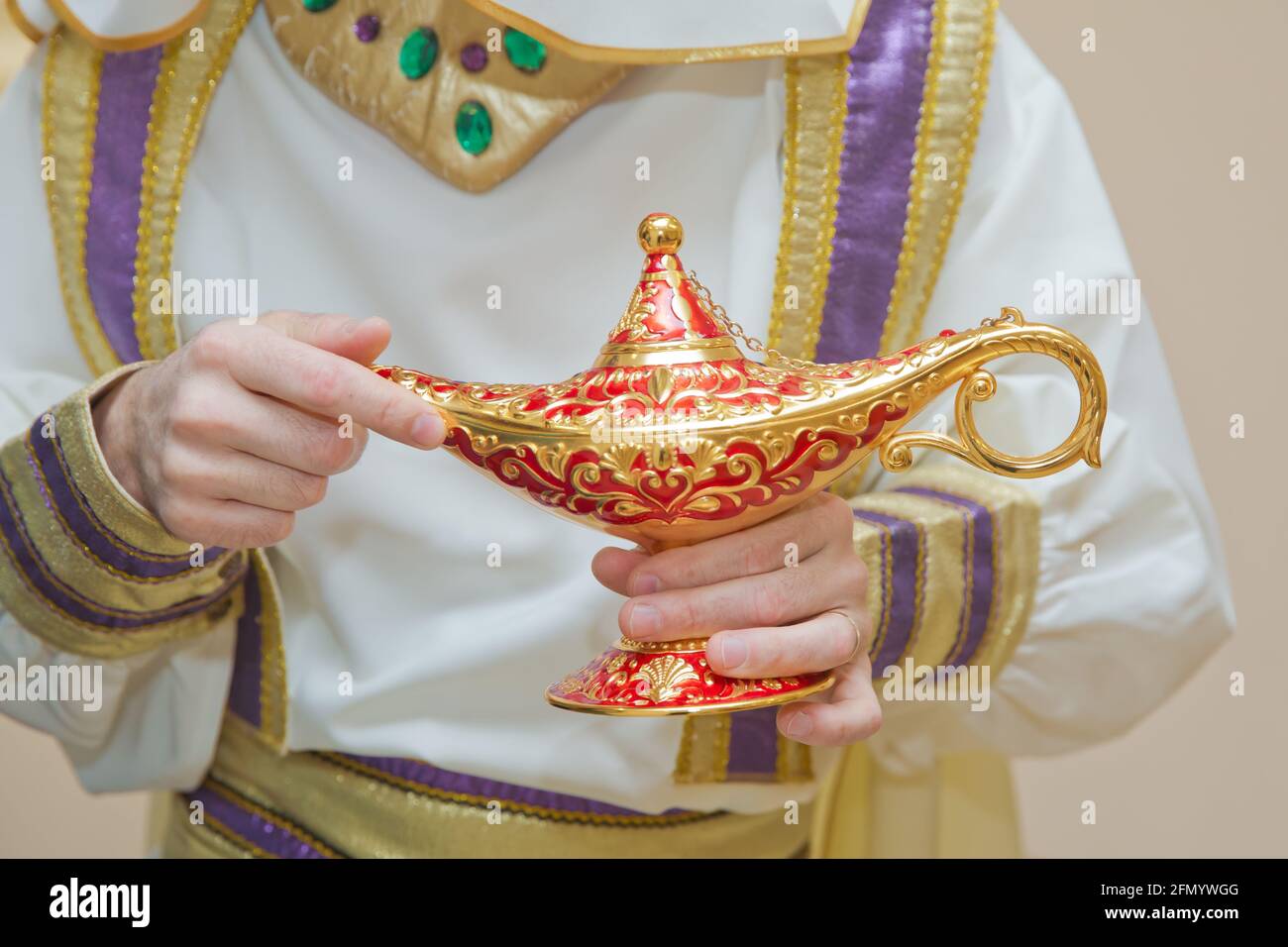 Un homme dans les vêtements d'Aladdin . Une personne tient dans sa main  lampe d'or réaliste d'Aladdin . Olds dans ses mains la lampe magique d' Aladdin. Tenant un vieux Photo Stock -