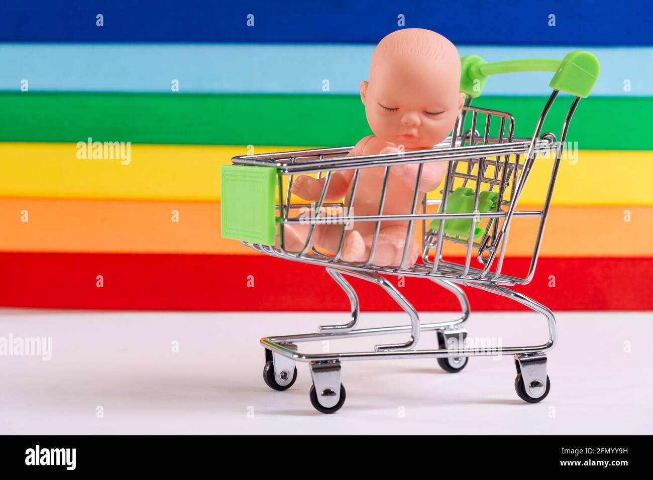 Communauté LGBT et enfants. Poupée bébé dans un panier sur le fond du drapeau LGBT, le concept de l'adoption, insémination artificielle. Banque D'Images