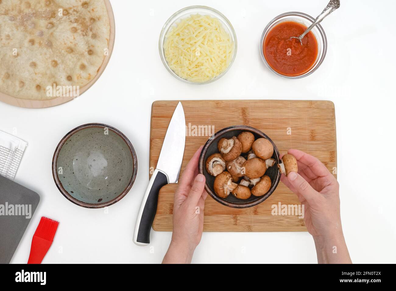 Les champignons Criminaux dans un bol se ferment sur une table de cuisine. Pizza avec mozzarella et recette de champignons, plat, mains de femme Banque D'Images