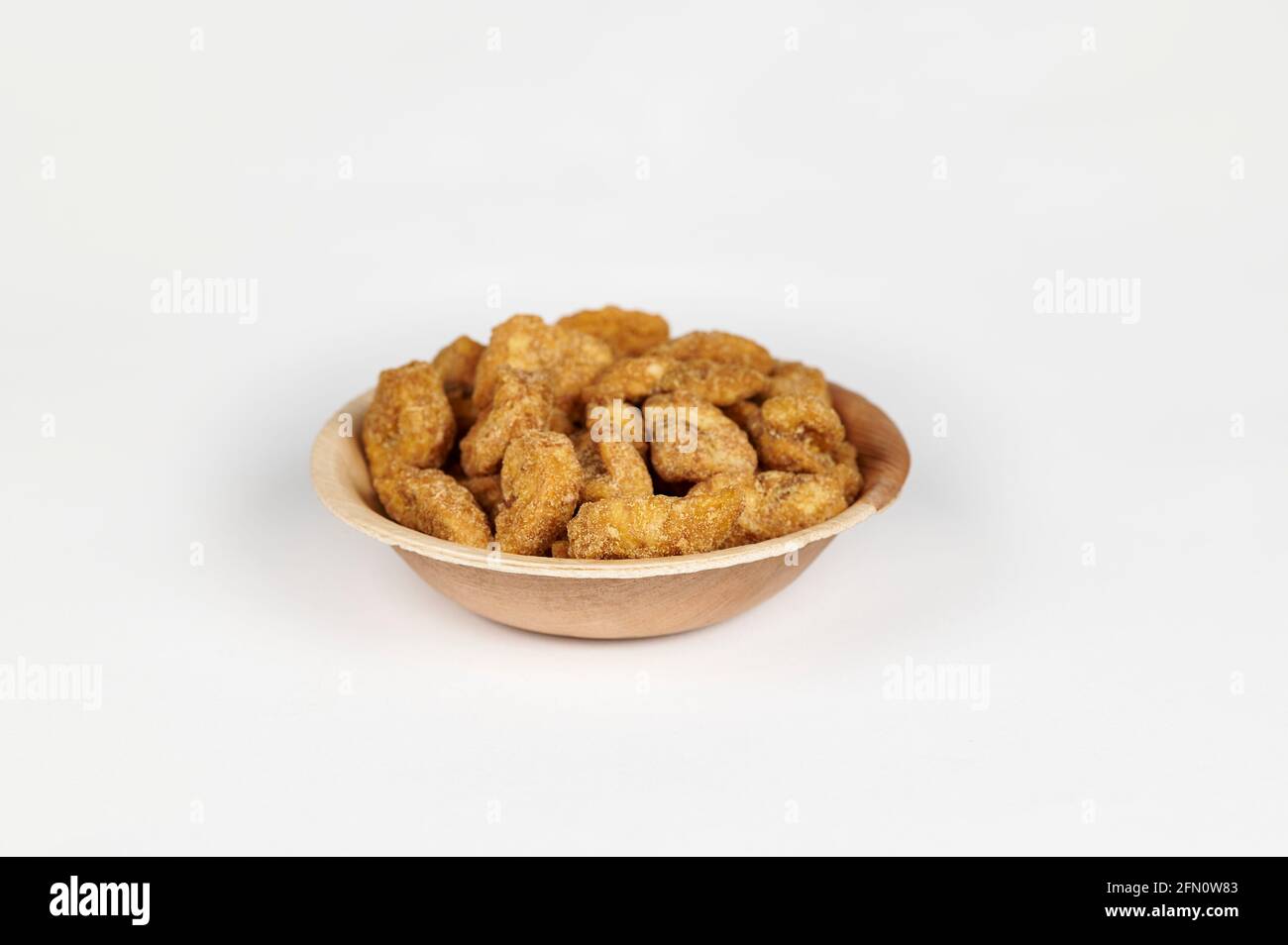 Croustilles de banane enrobées de jaggery ou sharkara varatti dans une areca bol à feuilles sur fond blanc Banque D'Images