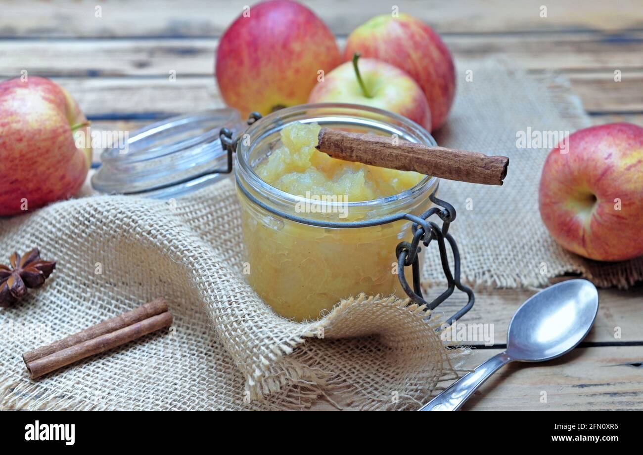 bâton de cannelle dans une sauce aux pommes maison dans une glasse bol avec pommes rouges sur table en bois Banque D'Images