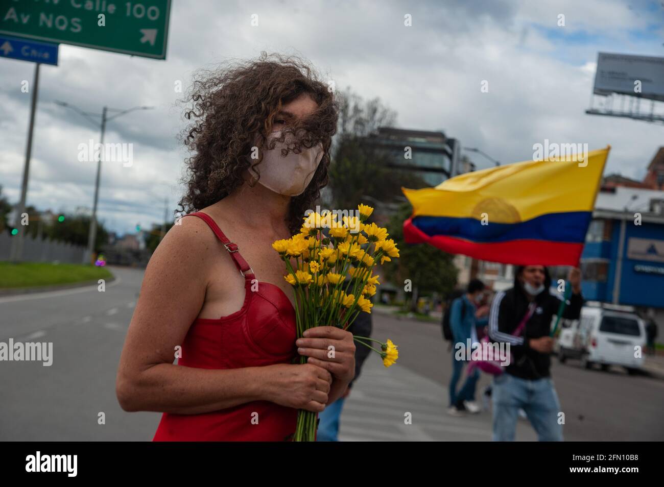 Bogota, Colombie. 12 mai 2021. Une femme se tient au milieu de la route avec une robe avec le drapeau colombien couleurs à l'envers et fleurs comme Bogota, La Colombie entre dans sa troisième semaine de manifestations antigouvernementales contre le président Ivan Duque Marquez et les morts qui s'résument à 40 cas de brutalité policière lors de la grève nationale, le 12 mai 2021. Crédit : long Visual Press/Alamy Live News Banque D'Images