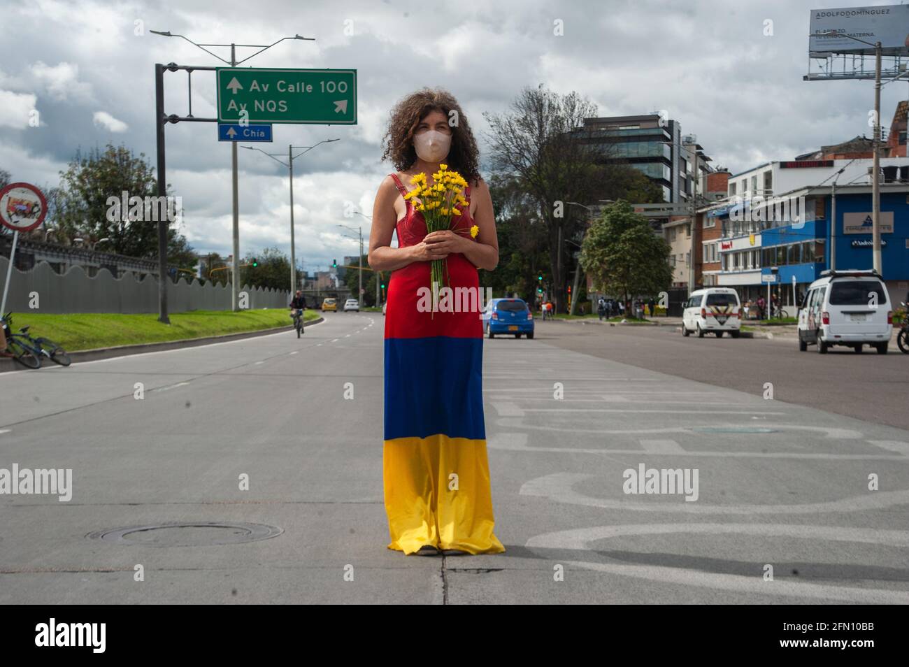 Bogota, Colombie. 12 mai 2021. Une femme se tient au milieu de la route avec une robe avec le drapeau colombien couleurs à l'envers et fleurs comme Bogota, La Colombie entre dans sa troisième semaine de manifestations antigouvernementales contre le président Ivan Duque Marquez et les morts qui s'résument à 40 cas de brutalité policière lors de la grève nationale, le 12 mai 2021. Crédit : long Visual Press/Alamy Live News Banque D'Images