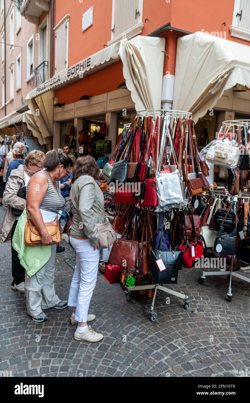 Les touristes admirant un rack de sacs à main en cuir italien Vente la petite ville de Garda sur la rive est Du lac de Garde dans la région de Vénétie du nord Banque D'Images