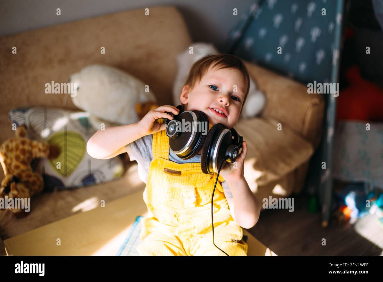 Drôle petit enfant s'amuser avec des écouteurs à la maison, portrait. Banque D'Images