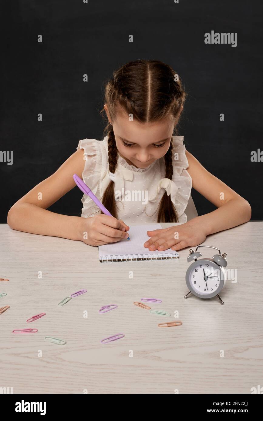 petite fille mignonne lisant un livre dans la salle de classe sur fond de tableau noir. Retour à l'école. Banque D'Images