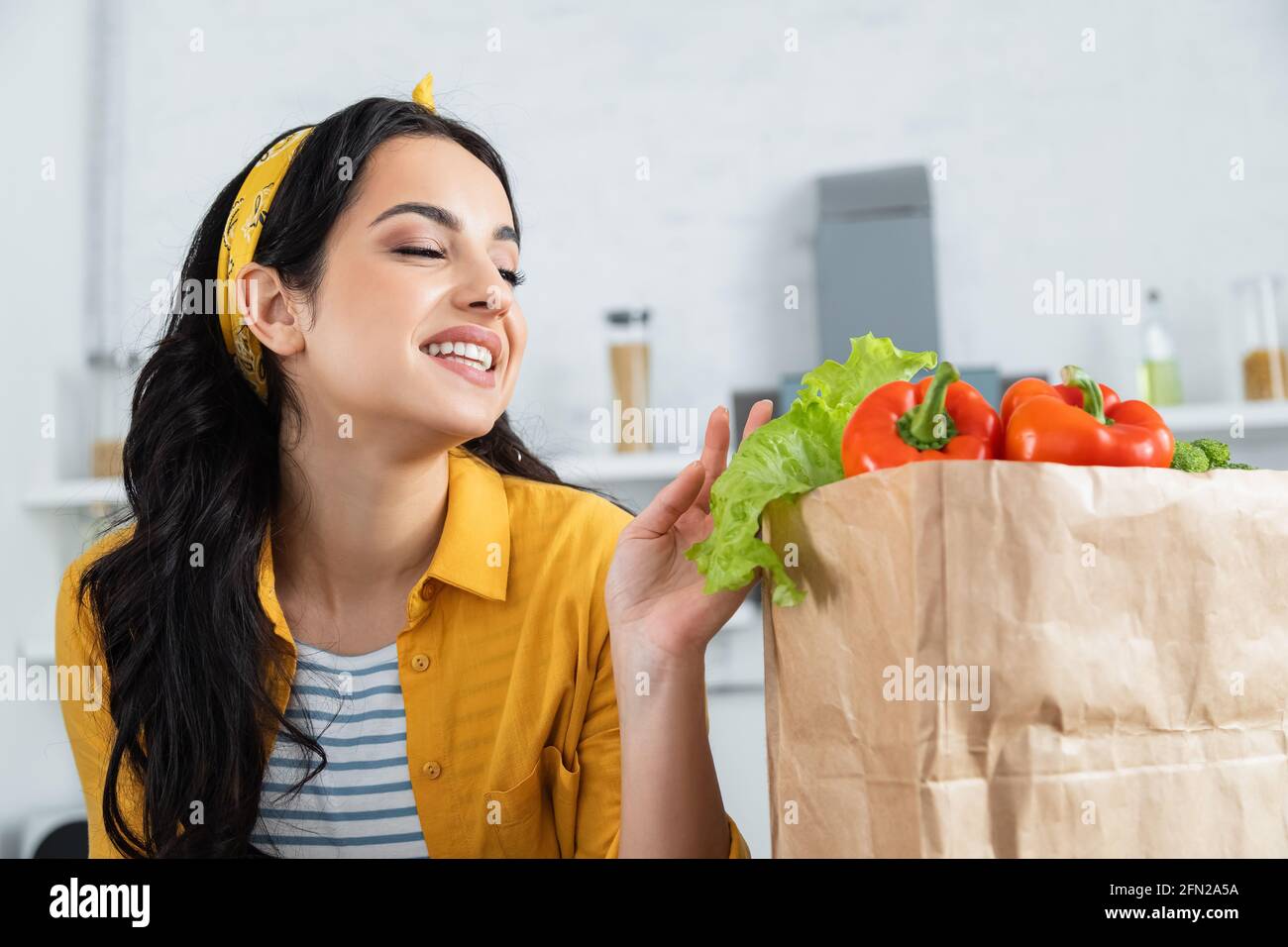 bonne femme brune regardant le sac en papier avec des provisions fraîches Banque D'Images