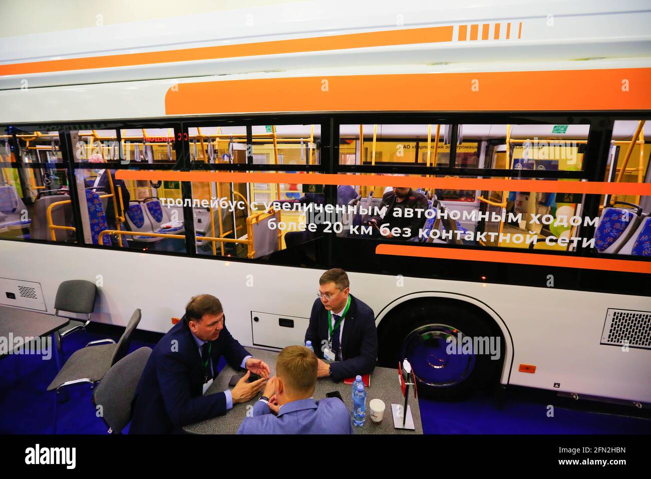 Moscou, Russie. 13 mai 2021. Les participants s'assoient à table près d'un bus électrique exposé lors de l'exposition internationale ElectroTrans sur le transport électrique urbain à Moscou, en Russie, le 13 mai 2021. L'exposition durera jusqu'au 14 mai. Credit: Alexander Zemlianichenko Jr/Xinhua/Alay Live News Banque D'Images