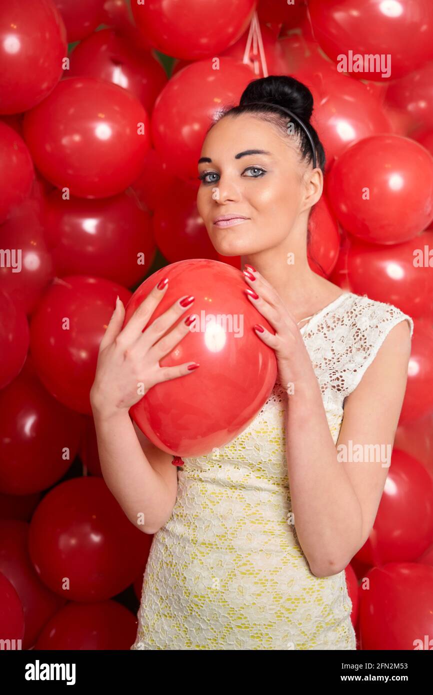 Belle fille de brunette jouant avec des balons rouges Banque D'Images