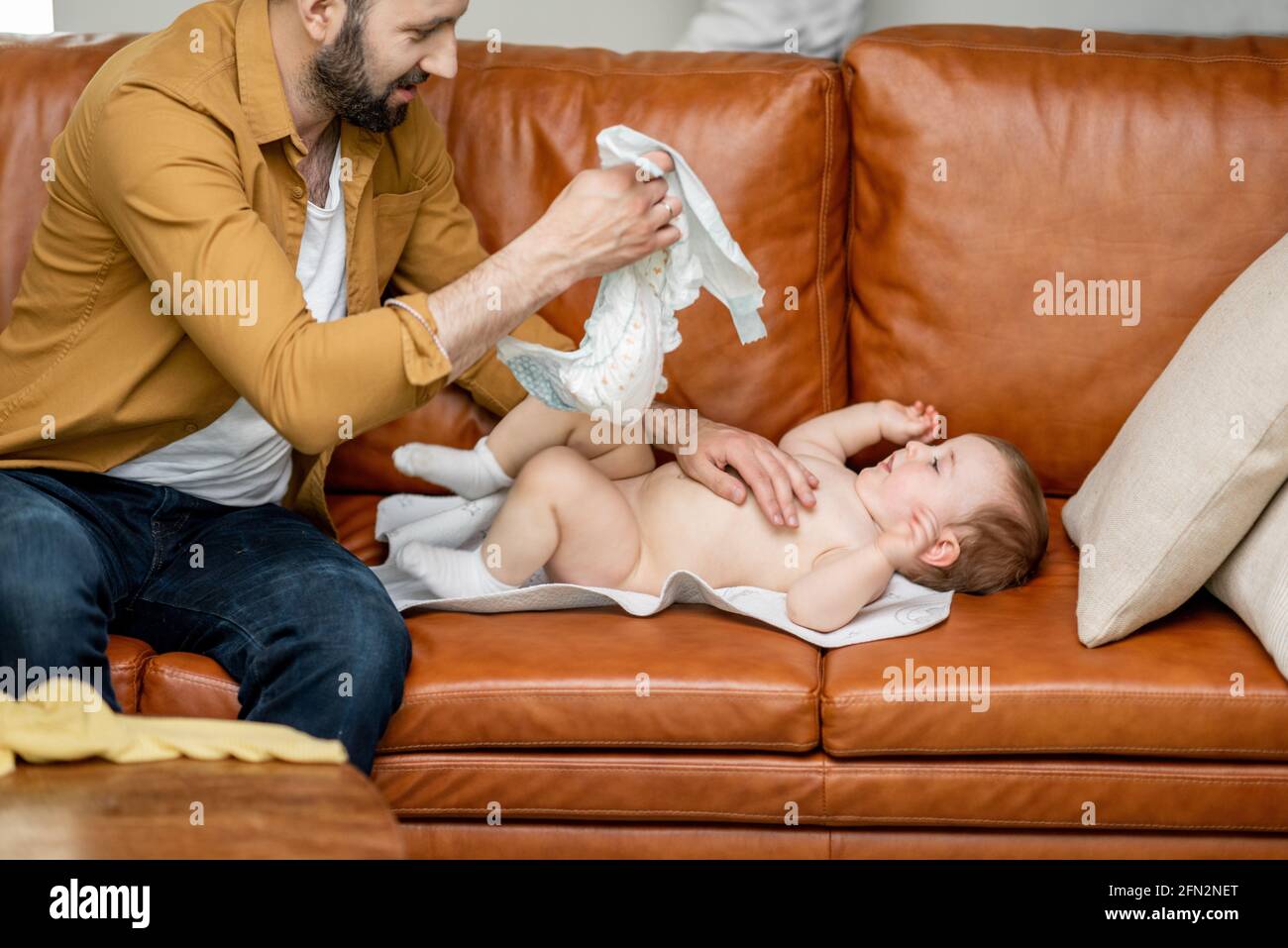 Père changeant de couche pour son fils bébé seul à la maison. Papa de baby-sitter et parent difficile. Banque D'Images