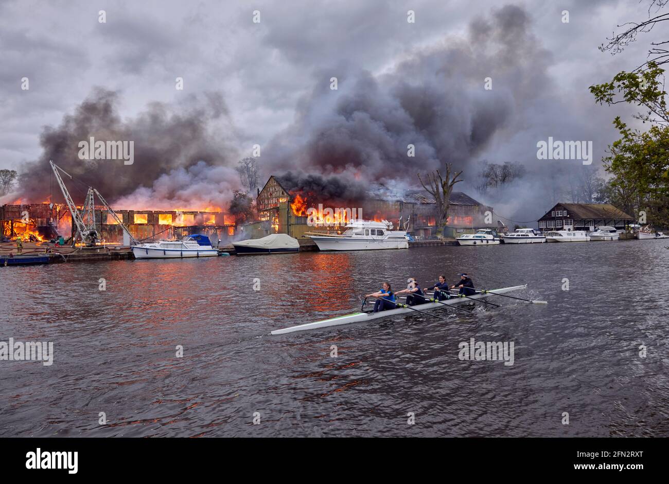 Rameurs de l'école secondaire de Wimbledon passant devant le feu d'Eyot de Platt Du 3 mai 2021 qui a détruit le hangar à bateaux de Otter Marine et l'évacuation de Dunkirk Banque D'Images