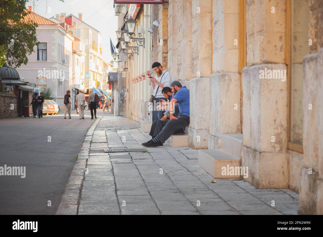 Mostar, Bosnie-Herzégovine - septembre 28 2014 : des hommes musulmans bosniaques locaux sur leurs smartphones dans les rues pavées historiques de la vieille ville de MOST Banque D'Images