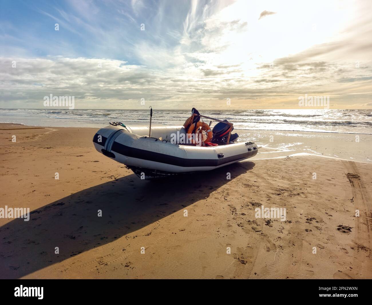Bateau gonflable à coque rigide avec moteur hors-bord sur la rive battue par les vagues. Utilisé pour pêcher en mer Banque D'Images