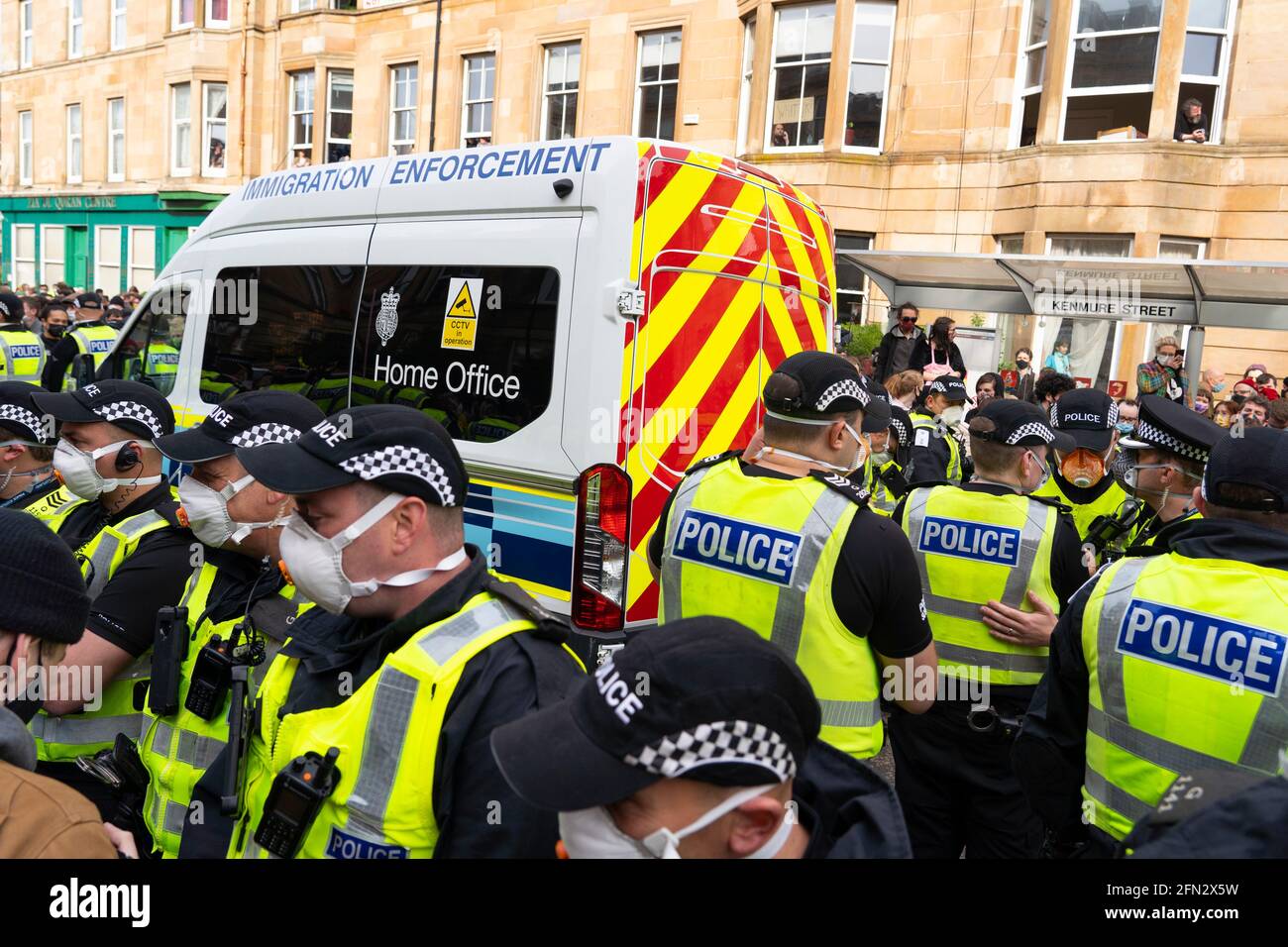 Glasgow, Écosse, Royaume-Uni. 13 mai 2021. À environ 5.30 heures, la police a libéré deux hommes d'un véhicule de détention du siège social. Accompagnés de l'avocat Amer Anwar, les hommes ont marché jusqu'à une mosquée voisine entourée de centaines de policiers et de partisans qui avaient auparavant entouré le véhicule et s'étaient assis dans la rue. Pic ; le véhicule de l'autorité de l'immigration du siège social, qui contient deux hommes, est entouré de manifestants. Crédit : Iain Masterton/Alay Live News Banque D'Images